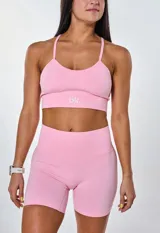 Conjunto deportivo color rosa compuesto por top con breteles finos y logo 'bk.' estampado en blanco, y calzas cortas tipo biker.