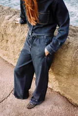 Pantalón de jean azul oscuro, de tiro medio, corte ancho y largo, estilo jogger con cintura elástica ajustable con cordones, bolsillos delanteros de vivo y bolsillos de parche en la espalda.