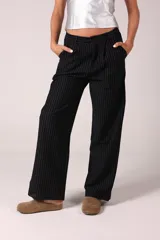 Pantalón sastrero negro con finas rayas verticales blancas, de corte clásico y pierna ancha.