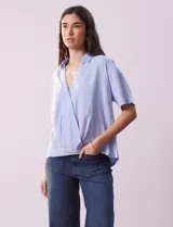 Blusa celeste de lino marca Cupio, con cuello con solapa, escote en V y delantera cruzada.