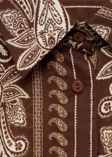Camisa marrón con estampado paisley en tonos beige, de corte recto, cuello camisero y mangas largas con puños abotonados.