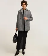 Saco alargado gris con cuello solapa, abotonado delantero y bolsillos. La prenda también cuenta con superfície en textura boucle.