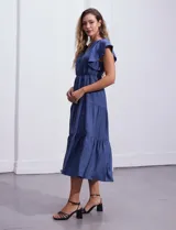 Vestido midi celeste de poliéster, con cuello a la base y escote en V. Presenta cintura con frunces y lazo de ajuste, mangas ranglan con sisa amplia y falda escalonada. Marca Emma & Michele.