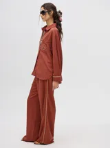 Pantalón de vestir color ladrillo, de corte holgado y tiro alto, con caída recta y detalle de diseño al costado.