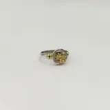 Anillo plateado con apliques dorados, con forma circular y diseño de cruz.