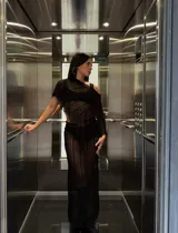 Poncho negro de mesh translúcido con diseño a rayas, calce asimétrico y flecos sutiles.