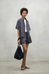 Short de lino color gris oscuro con cintura elástica fruncida y cordón de ajuste frontal. Presenta bolsillos laterales y un calce holgado confeccionado en tejido de bambula, ideal para el verano.