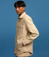 Camisa marrón de manga larga, confeccionada en sarga, con cuello inglés, abotonado delantero, bolsillos en el pecho con solapa y puños abotonados.