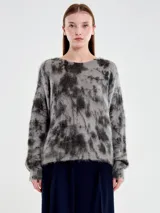 Buzo de punto con diseño jaspeado en tonos gris y negro, de cuello amplio y corte holgado. Confeccionado en una mezcla de mohair y lana que le otorga una textura suave y afelpada.