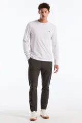 Remera de manga larga color blanco, con cuello redondo y un pequeño logo bordado de pingüino en el pecho.