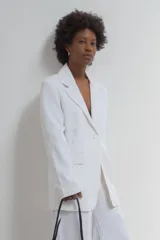 Blazer de lino blanco oversized con hombreras y bolsillos sastreros, ideal para looks de verano.