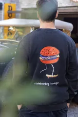Buzo negro de algodón con estampa de hamburguesa andando en skate.