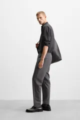 Pantalón color arena de corte recto, confeccionado en tejido elástico. Cuenta con cintura elástica ajustable con cordón, bolsillos laterales y bolsillos de vivo en la parte trasera.