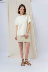 Minifalda de denim color crema con volados en los bolsillos delanteros y en el ruedo.