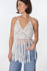 Top blanco de crochet con escote en V, tirantes finos y flecos.