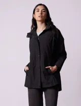 Campera impermeable color gris claro, marca Gallery. Tiene abertura central con cierre oculto y botones a presión, bolsillos delanteros y capucha plegable en el cuello.