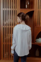 Camisa blanca de lino con cuello babero de broderie y mangas largas.