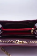 Cartera tipo sobre color beige con textura granulada y correa de cadena dorada.