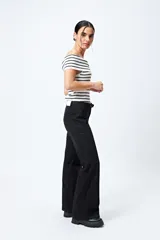Pantalón de jean azul oscuro, de corte flare con cinturón incorporado en la misma tela y silueta ajustada en cadera que se ensancha hacia el ruedo.