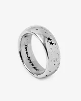 Anillo de banda ancha plateado con acabado envejecido y textura de salpicaduras oscuras. Presenta dos estrellas caladas en el exterior y la inscripción "Two Jeys" grabada en el interior.