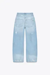 Pantalón de jean celeste claro, corte baggy, tiro medio, largo hasta el tobillo y con roturas grandes en ambas piernas.