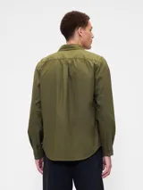 Camisa de manga larga color beige, de corte clásico, con cuello abotonado, bolsillo en el pecho y logo de oso bordado.