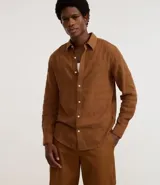 Camisa de hombre color marrón óxido, de corte regular, confeccionada en una mezcla de algodón y lino con textura grid. Presenta cuello inglés, manga larga y cierre frontal con botones blancos.