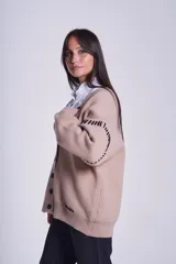 Cárdigan color beige con botones negros, escote en V y detalles de costuras bordadas en negro.