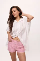 Camisa blanca de manga corta con cuello clásico, corte holgado y detalle de calado vertical en el frente.