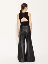 Pantalón de cuero vacuno negro, de silueta amplia con recortes diagonales en delantero y espalda. Tiene un complemento de lino al tono aplicado en los laterales.