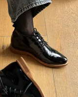 Zapato acordonado de cuero vacuno color negro con suela de madera.
