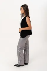 Pantalón plateado de tiro alto confeccionado en gabardina stretch metalizada, con bolsillos y cierre frontal con cremallera y botón.