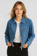 Chaqueta de jean azul con cuello clásico, cierre frontal con botones metálicos, bolsillos con solapa en el pecho y corte holgado.