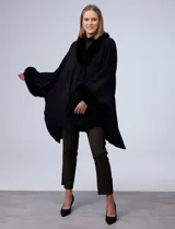 Ruana o poncho negro de tejido suave, con cuello y puños adornados con apliques de piel sintética (faux fur).