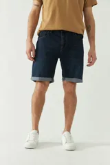 Bermuda de jean azul oscuro con bolsillos delanteros y traseros, presillas para cinturón y dobladillo en el ruedo.