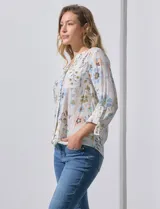 Blusa de gasa estampada con rayas verticales en tonos naranja, amarillo y blanco. Tiene cuello a la base, escote en V y botones. Delantera con bolsillo aplicado. Largo de manga regulable con presilla y botón. Terminación anudada opcional.