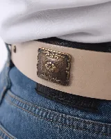 Cinturón de cuero color beige con hebilla ovalada y apliques metálicos color bronce.