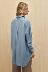 Vestido camisero negro de silueta amplia, con cuello camisero, botonadura frontal completa y mangas largas.