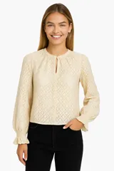 Blusa beige claro con textura calada, cuello redondo con abertura en forma de gota y mangas largas abullonadas con puños elastizados.