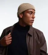 Gorro corto tipo beanie color beige, tejido en lana acrílica con textura acanalada.
