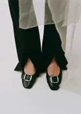 Zapato de cuero negro con tacón bloque y hebilla decorativa.