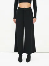 Pantalón negro de corte palazzo con cintura alta y botón.