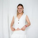 Chaleco corto color crema con escote en V, sisa redonda y cierre delantero con botones.