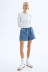 Short de denim azul claro, con cintura elástica y cordón ajustable. De corte holgado con bolsillos laterales y bajo recto con abertura lateral corta.