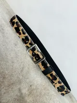 Cinturón de cuero con estampado animal print, hebilla cuadrada plateada y reverso negro.