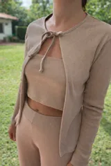 Saco de tejido ligero color beige, de manga larga y corte abierto, con cuello redondo.