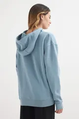 Buzo hoodie lila con capucha y cordones ajustables, bolsillo tipo canguro y corte holgado.