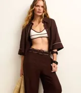 Pantalón wide leg de cintura alta color marrón, confeccionado en viscolino con 15% de lino, con trabillas en la cintura y vieses contrastantes en las barras. Incluye cinturón de tejido con hebilla metalizada de efecto martillado.