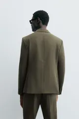 Blazer slim fit color verde oliva confeccionada en tejido con viscosa. Cuello con solapas de muesca, manga larga acabada en puño con detalle de botones, bolsillo de vivo en pecho y de solapa en cadera. Detalle bolsillo interior, bajo con aberturas en espalda y cierre frontal con botones.