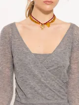 Sweater gris compuesto por un top inferior de breteles y un sweater superior de manga larga con escote en V cruzado. Ambas piezas están confeccionadas en tejido liviano de lana mezclada.